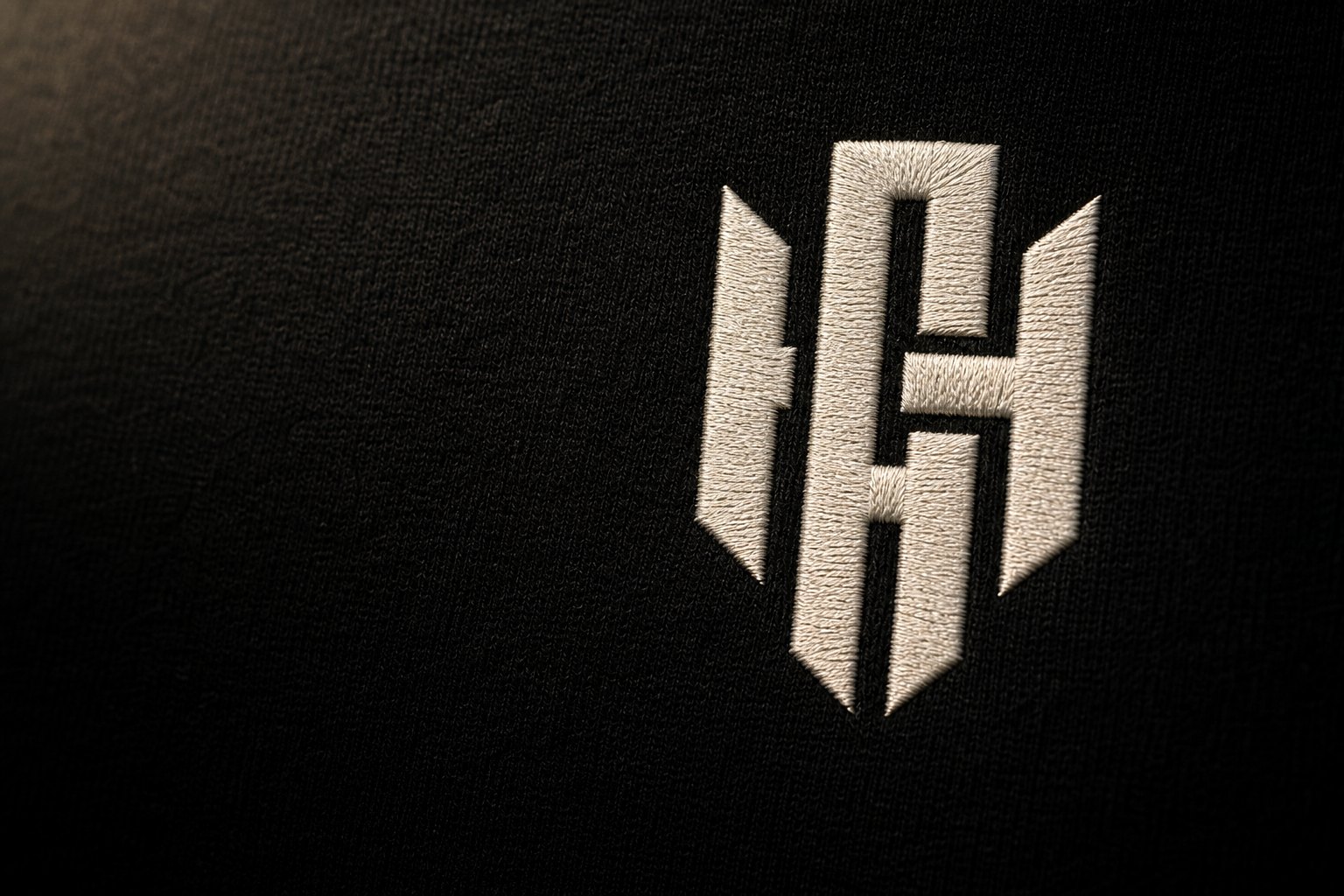 Macro of the Hayes monogram embroidered in bone thread on black fabric